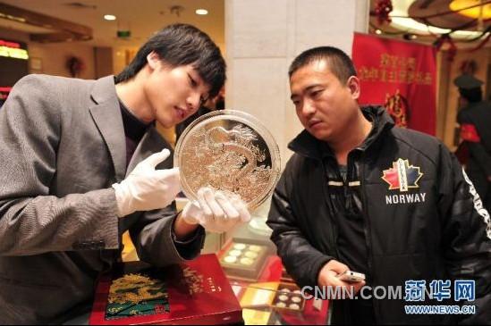 12月21日，工作人員向顧客介紹一款5公斤重的壬辰賀歲紀(jì)念大銀章，其正面的“金龍降喜”圖案，寓意對(duì)龍年萬(wàn)事亨通的美好祝福。